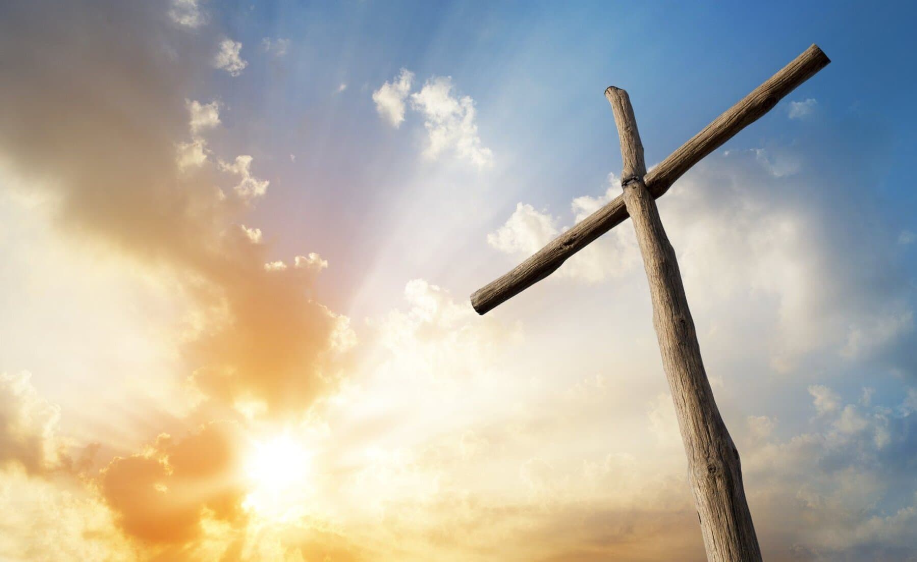 Ein Holzkreuz vor strahlend blauem Himmel mit warmem Sonnenlicht